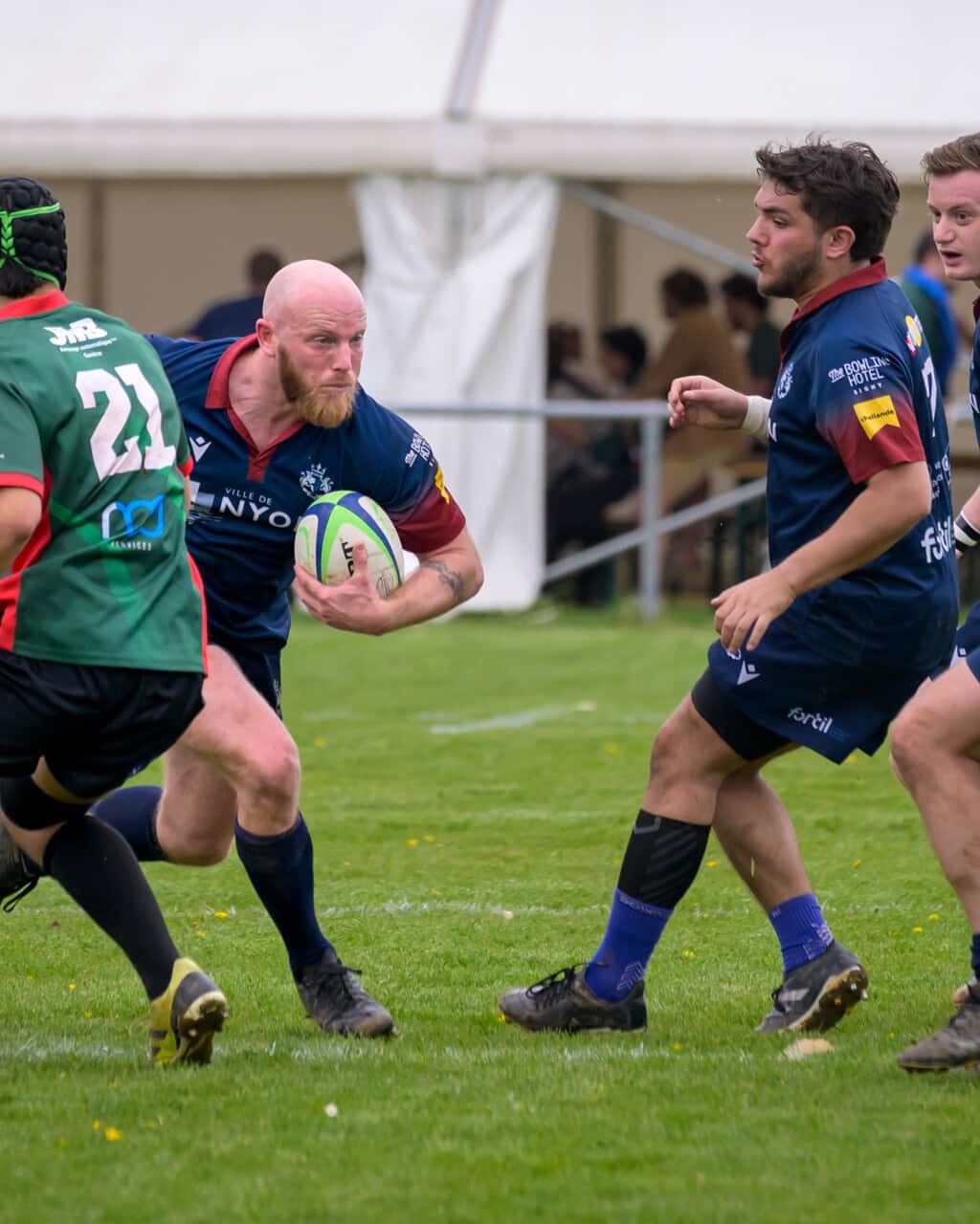 joueurs du Nyon RC qui fait une percée avec le ballon ovale contre Hermance